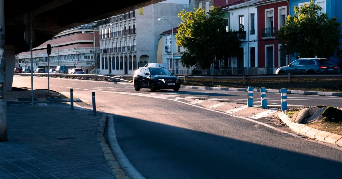 Une rue urbaine animée avec des voitures passant sous une route élevée. Présentant une architecture colorée.