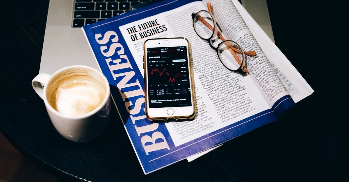 Un environnement professionnel avec un ordinateur portable, du café, un téléphone et un journal. Parfait pour des thèmes financiers.