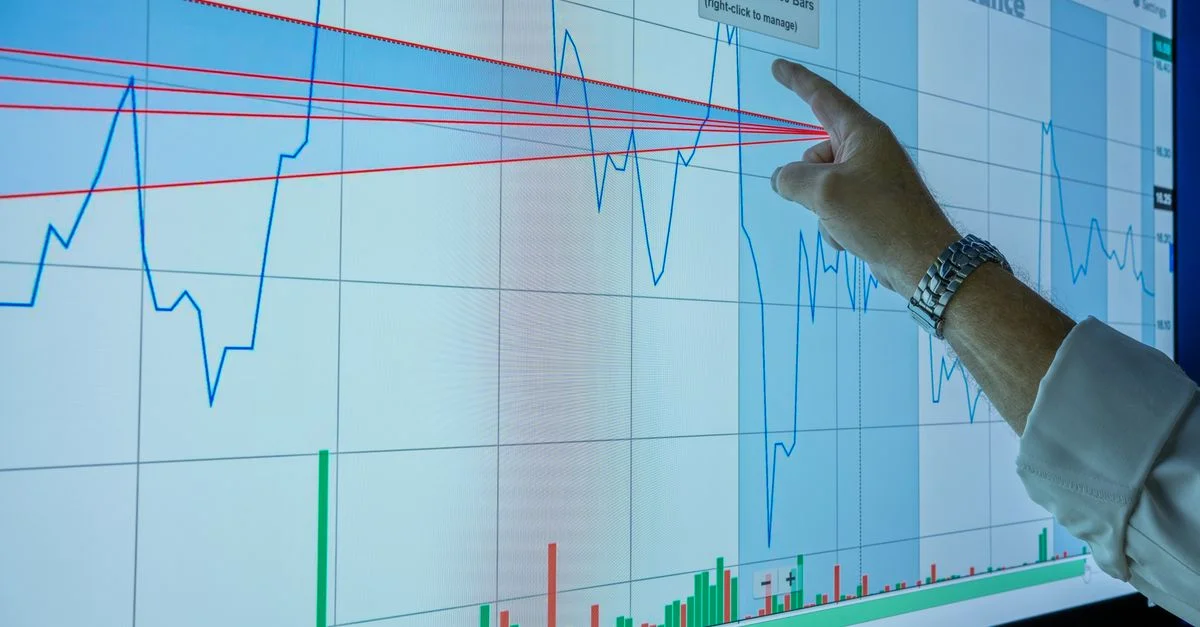 Gros plan sur une main analysant un graphique financier sur un écran numérique pour en déduire les tendances du marché et des informations sur les investissements.